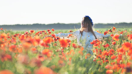 Ukrainian girl walking through a red poppy field.の写真素材