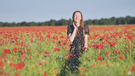A young girl walks through a red poppy field.の写真素材