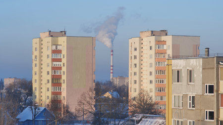 Houses of the residential area against the background of the smoky boiler house chimney.