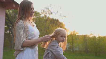 A loving mother touches her daughters hair at sunset.の写真素材