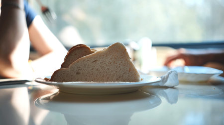 People have lunch on the train. Sandwiches in a plate in the foreground.