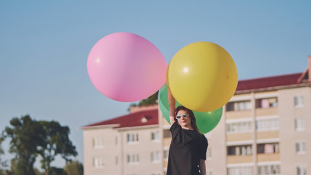 Happy girl with big with colorful balloons posing on the background of city houses.の写真素材
