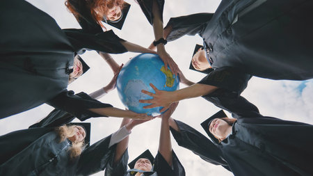 Graduating students embrace a geographical globe of the world. The concept of preserving peaceの写真素材