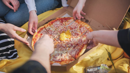 A group of hands reach for the pizza.の写真素材