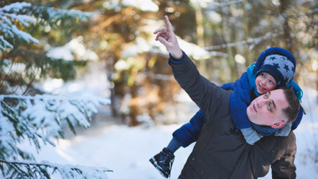 A father and his young son are walking through a winter forest.の写真素材