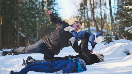 A mother and her child playing in the winter woods, falling in the snow with him.の写真素材