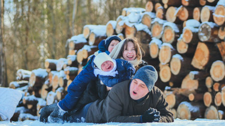 A happy family lying in the snow on a winters day.の写真素材