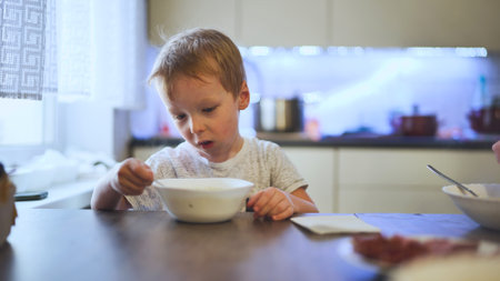 A child stirring hot soup at the table.の写真素材