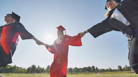 College graduates holding hands run in a round dance.