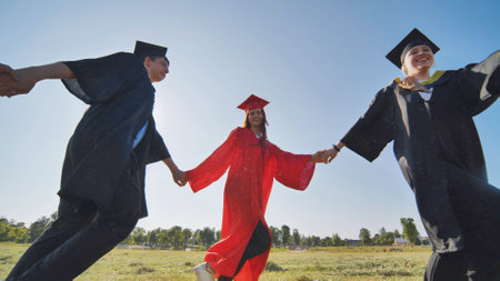 College graduates holding hands run in a round dance.の写真素材