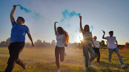 A group of friends spraying multi-colored smoke at sunset.の写真素材
