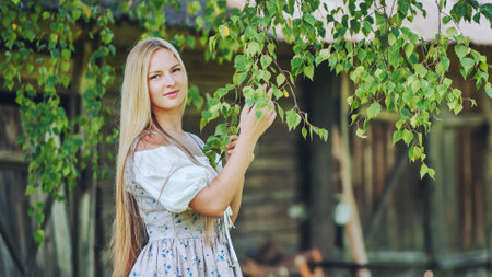 German girl posing by the branches of a birch tree.の写真素材
