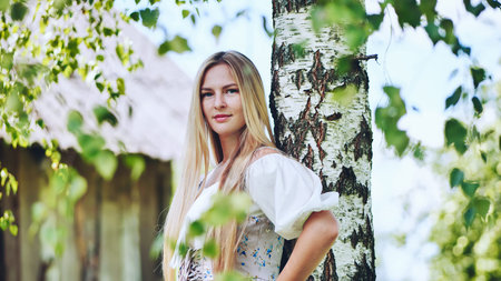 Slavic girl posing by a birch tree.の写真素材