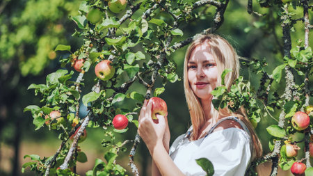 A young woman in paradise posing by the branches of an apple tree.の写真素材
