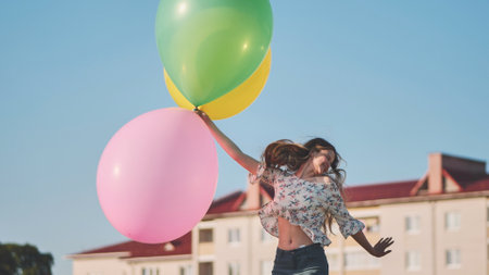 A girl happily poses with large with colorful balloons in the city.の写真素材
