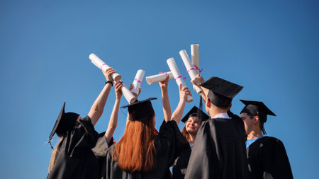 College graduates with caps tie their diplomas together.の写真素材
