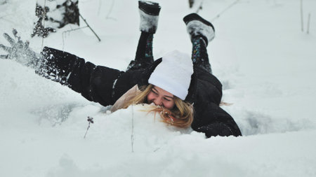 A girl falls on the snow in winter in the forest.の写真素材