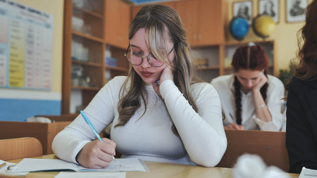 A high school student sits at her desk.