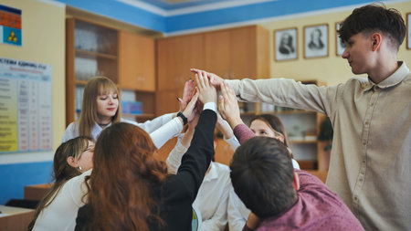 High school seniors join hands in class as a sign of working together.