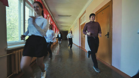 A down-syndrome school boy with group of children in corridor, running.の写真素材