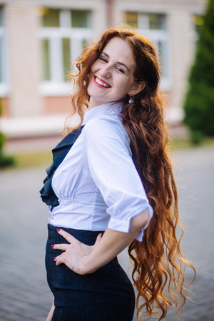Portrait of a redhead high school student against the backdrop of the school.