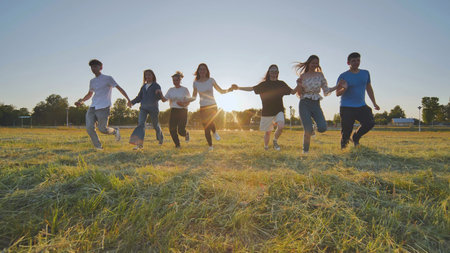 Young boys running at sunset across the field holding hands.