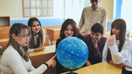 Students look at a globe of the starry sky in a classroom at school.