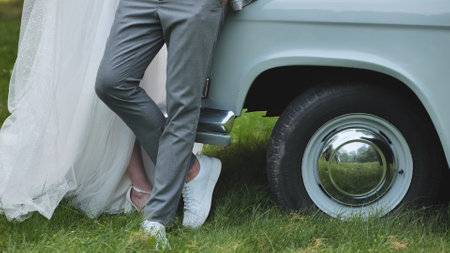 The bride and groom pose by a retro car on their wedding day.の写真素材