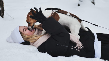 A girl playing with her Jack Russell Terrier dog in the snow.の写真素材