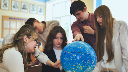 Students look at a globe of the starry sky in a classroom at school.の写真素材