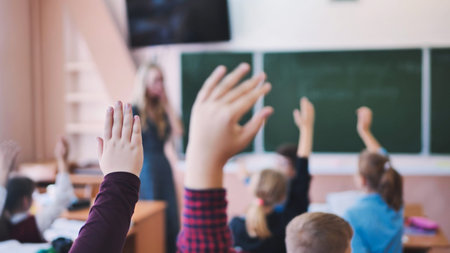 Elementary school students raise their hands during class.