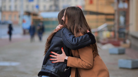 Two best friends meet on the streets of the city and hug.