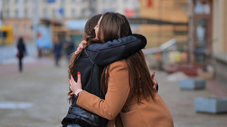 Two best friends meet on the streets of the city and hug.