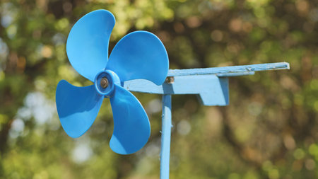 A blue vane weathervane spins in the wind in the summer.の写真素材