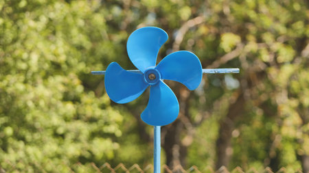 A blue vane weathervane spins in the wind in the summer.の写真素材