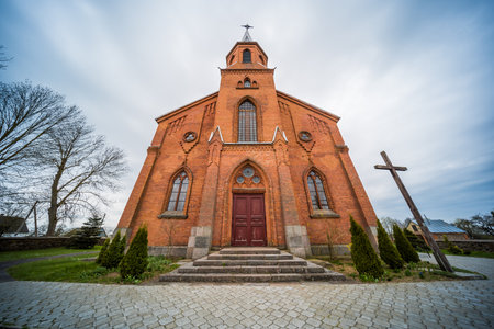 Red brick church facade with steeple towering under cloudy skyの写真素材