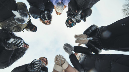 Friends standing in a circle tossing snow up.の写真素材