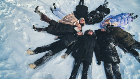 Friends lie in the snow on their backs in a circle shape.の写真素材