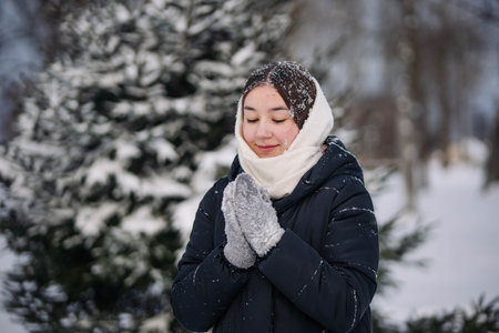 Schoolgirl in a winter forest wearing gloves and scarf to keep warm