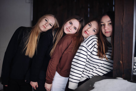 Group of four young women posing for a winter photoshoot, showcasing their friendship and leaning on each otherの写真素材