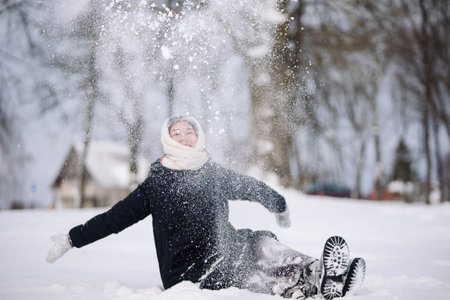 Schoolgirl playing with snow and throwing it in the air in a snowy winter landscapeの写真素材