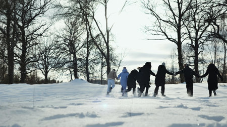 Schoolgirls and teachers linked arms and running through a winter wonderland during a photoshoot in the snowの写真素材