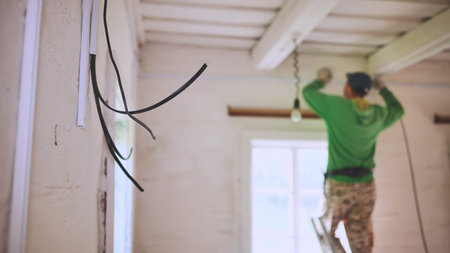 An electrician conducts wiring in a wooden house.