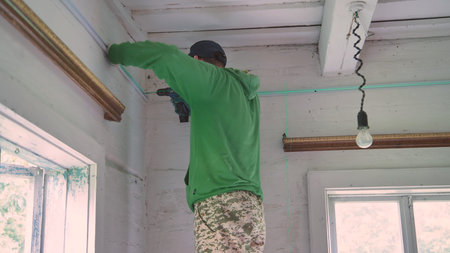 An electrician conducts wiring in a wooden house.