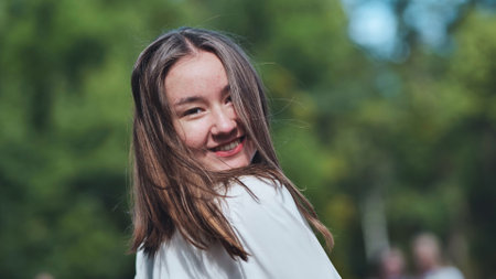 Happy student girl smiling and looking back in the park on her first day of schoolの写真素材