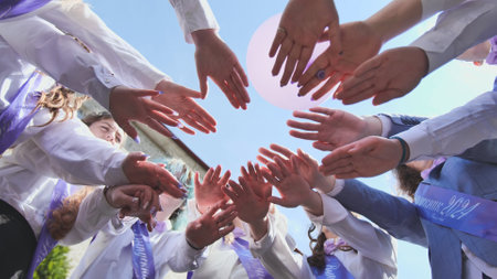 Students forming a circle, uniting in celebration of their graduation and last day of school in 2024, representing solidarity and camaraderieの写真素材