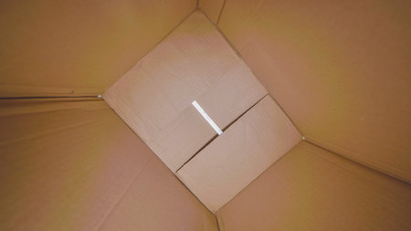 Anticipation and possibility shine through a partially opened cardboard box as light peeks in