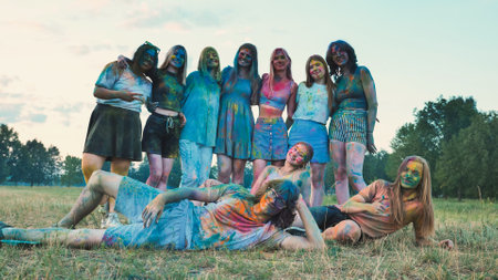 Graduates celebrating their achievement with colorful powder paint in a grassy fieldの写真素材