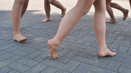 Ballet dancers happily stroll barefoot on pavement after school, feeling freedom and togetherness,...