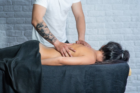 Male masseur makes back massage for a young girl.の写真素材